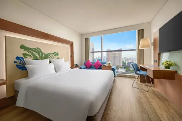 A double bed made up in a modern hotel room, city skyline through the floor to ceiling window